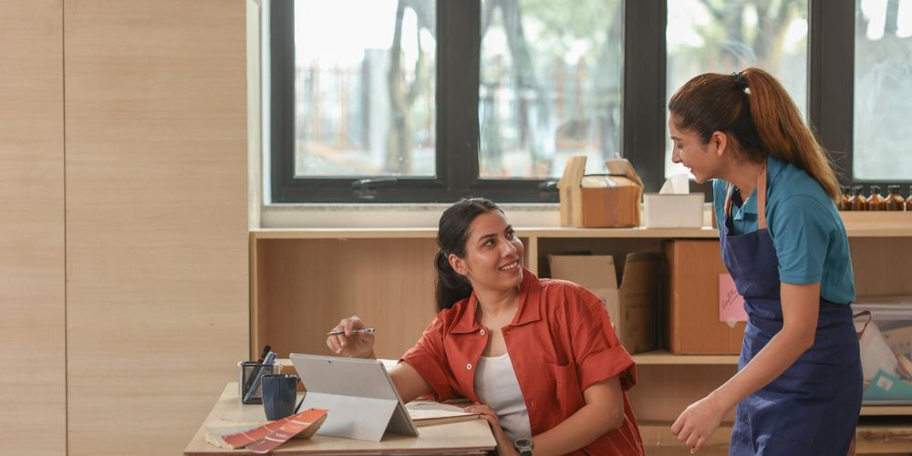 Dos mujeres organizando el trabajo de un pequeño negocio con una tablet.
