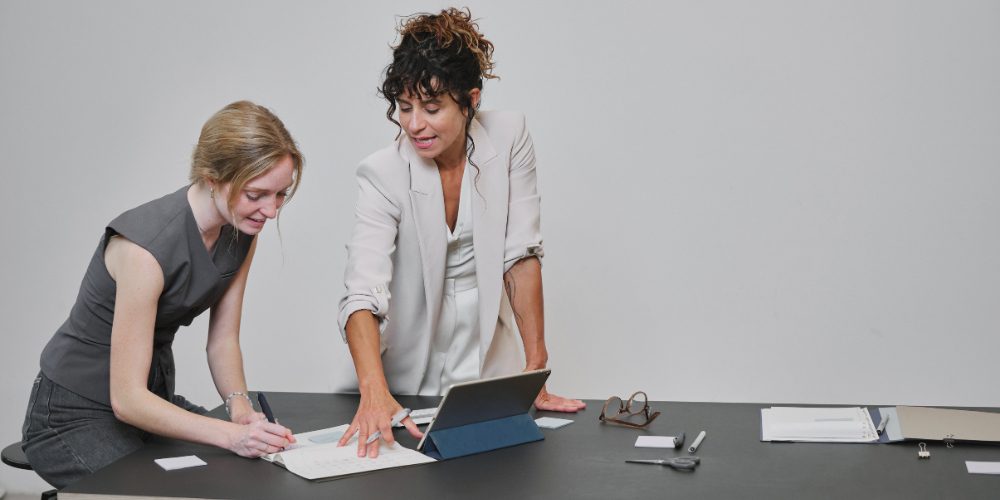 Dos personas revisando documentos junto a una tablet