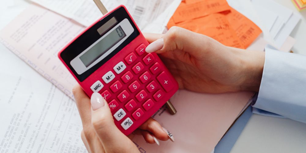 Persona calculando un presupuesto con calculadora y documentos.