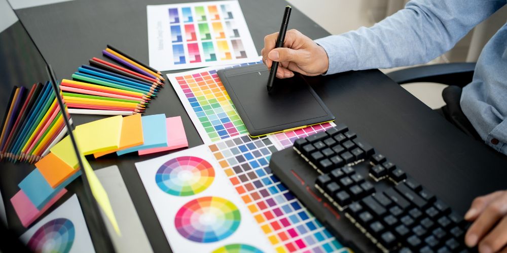 Persona utilizando una tableta gráfica junto a muestras de colores.