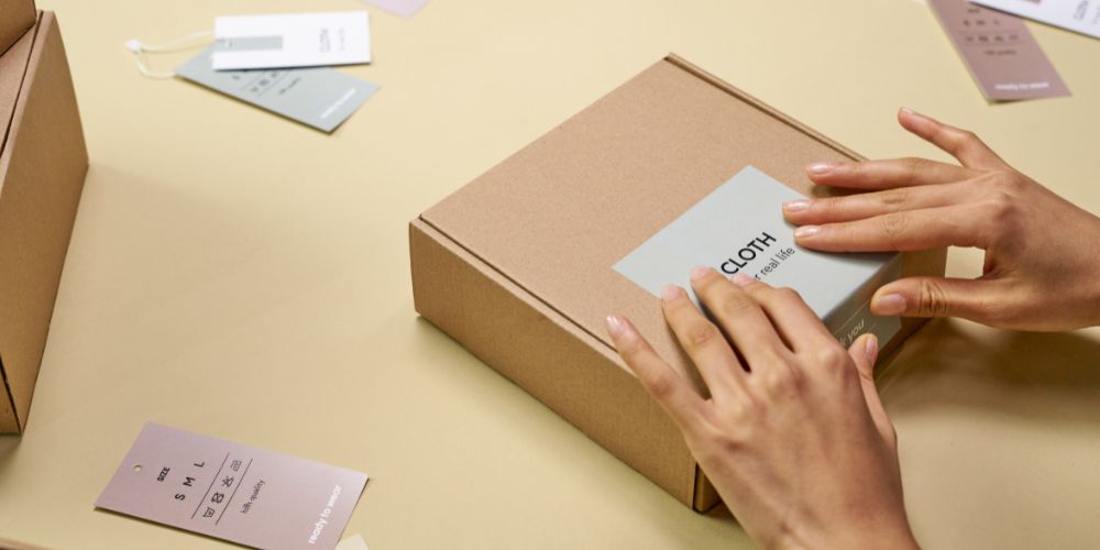 Manos colocando una etiqueta en una caja de cartón.