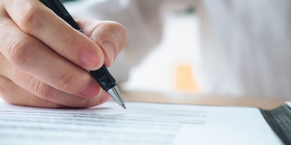 Primer plano de una mano con un bolígrafo sobre un documento.