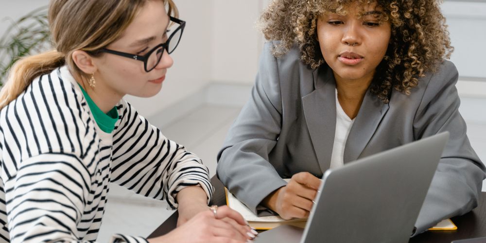 Dos mujeres revisando información en un computador portátil.