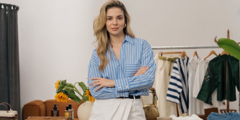 Mujer de pie con los brazos cruzados en una tienda de ropa y accesorios