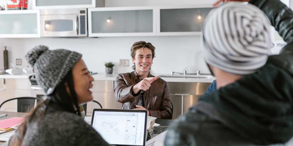 Personas conversando alrededor de una mesa con un computador portátil.