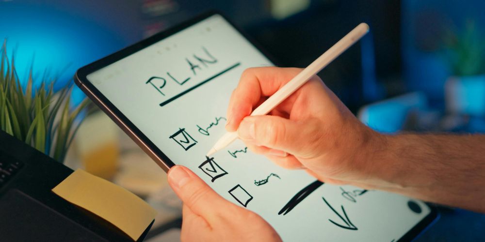 Persona marcando tareas de un plan en una tablet con un lápiz digital.