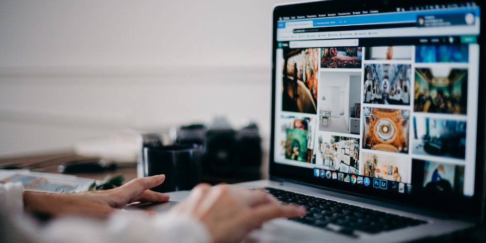 Persona revisando fotografÃas en un computador para preparar contenido visual para redes sociales.