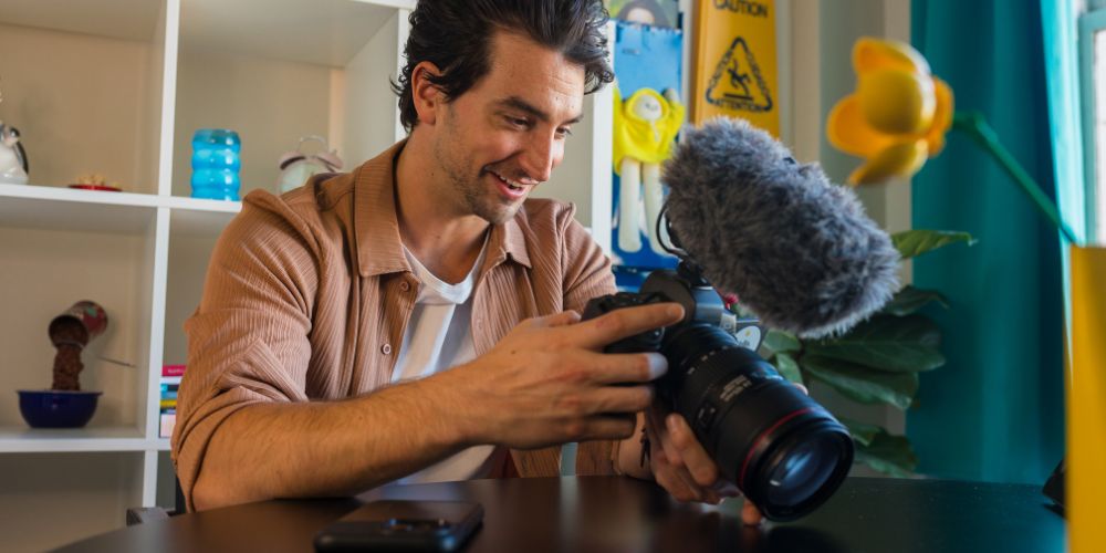 Hombre preparando una cámara con micrófono para crear contenido para redes sociales.