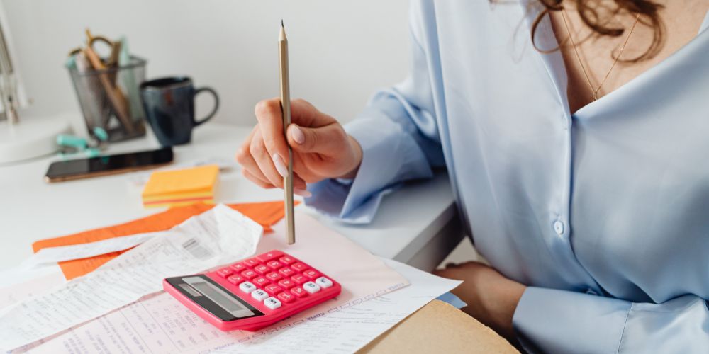 Persona revisando comprobantes y realizando cálculos con una calculadora.