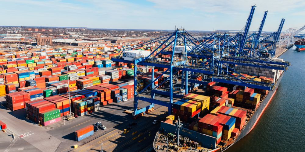 Puerto con contenedores, grúas y un buque de carga para transporte marítimo internacional.
