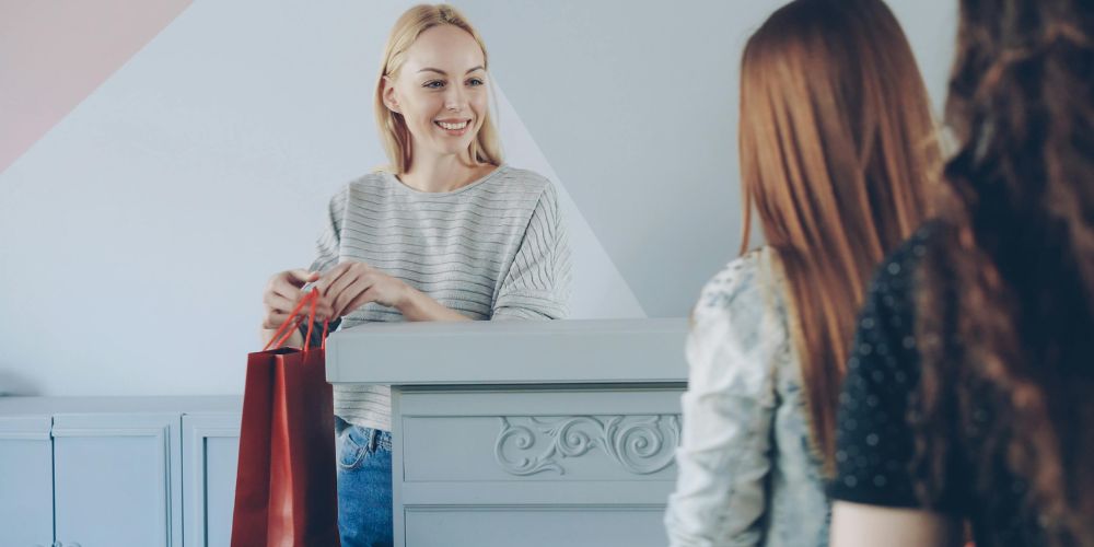 Atención al cliente en una tienda, con entrega de una bolsa de compras.