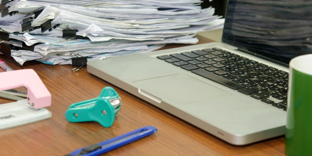 Documentos apilados junto a un computador para la gestión contable