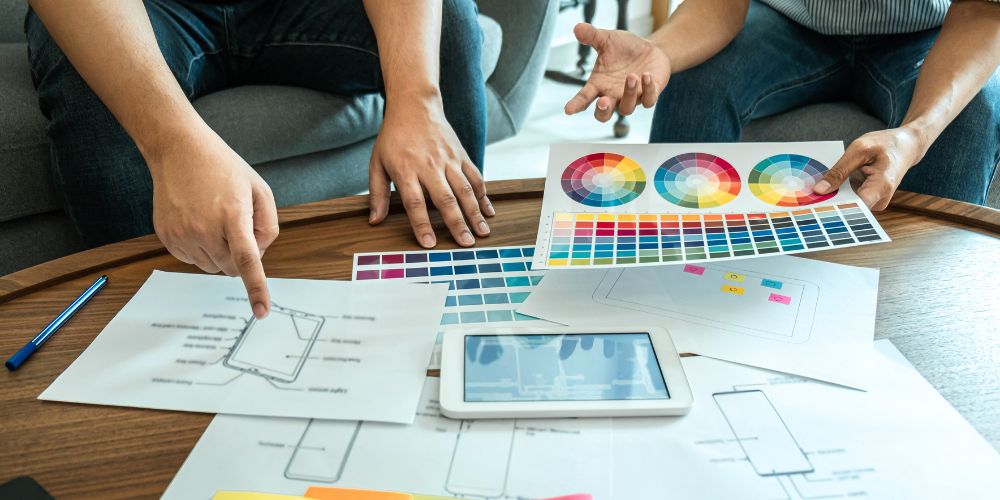 Personas revisando bocetos y paletas de colores para desarrollar una identidad visual de marca.
