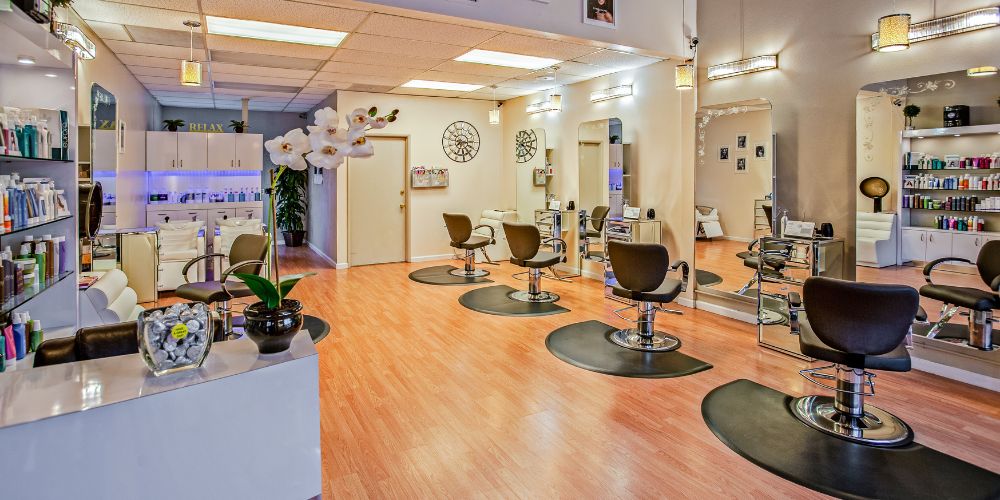 Interior de una peluquería con sillones, espejos y estanterías de productos capilares.