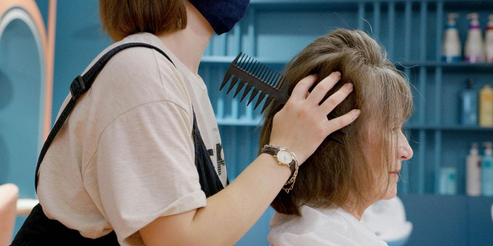 Peluquera peinando el cabello de una clienta en un salón.